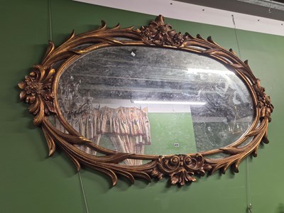 Lot 919 - An oval mirror within a gilt foliate frame...