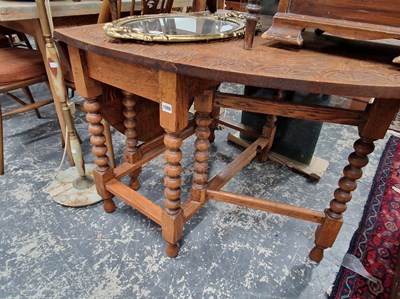Lot 1088 - A vintage oak gate legged table with carved...