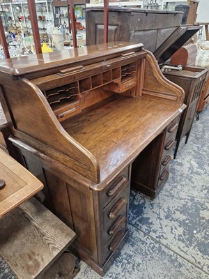 Lot 1409 - An oak s-roll top desk on four drawer pedestals.