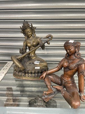 Lot 1135 - An Indian bronze goddess seated on a double...