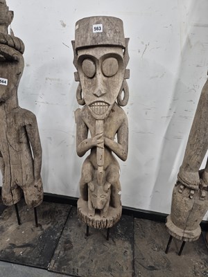 Lot 563 - An indonesian carved figure seated on a dog....