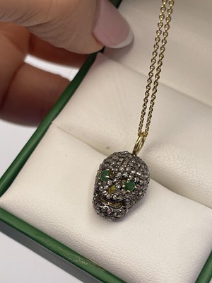 Lot 298 - A diamond set skull pendant with emerald eyes...