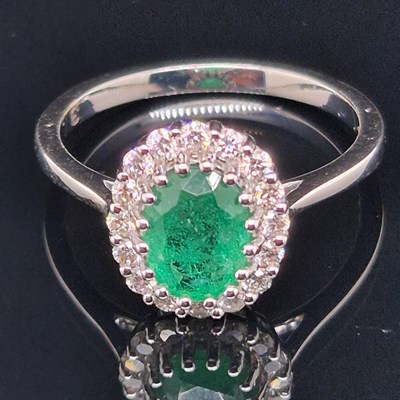 Lot 29 - An emerald and diamond cluster ring. The...