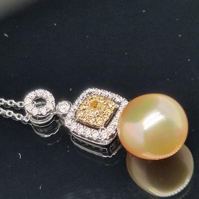 Lot 54 - A diamond and pearl pendant. The champagne...