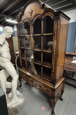 Lot 587 - A walnut display cabinet with a wavy top over...