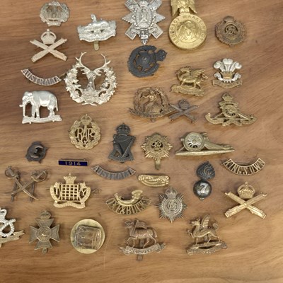 Lot 546 - A collection of cap badges and textile...