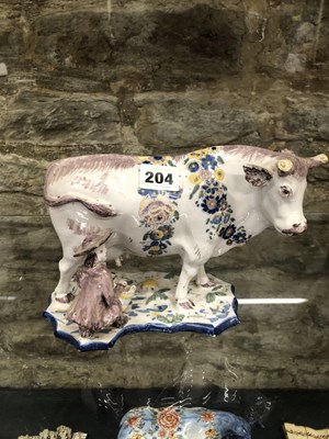 Lot 204 - A Dutch polychrome Delft floral garlanded cow...