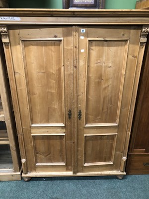 Lot 51 - A pine wardrobe with panelled doors enclosing...
