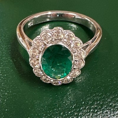 Lot 1032 - An 18ct white gold ring with an oval emerald...
