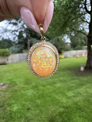 Lot 1202 - An opal and diamond pendant, centred by an...