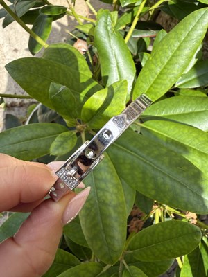Lot 1133 - A 9ct hallmarked white gold buckle-form hinged...