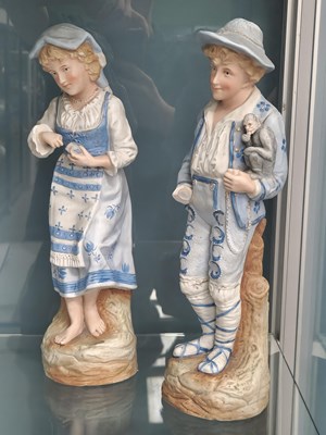 Lot 541 - A pair of bisque figures, he with a monkey on...