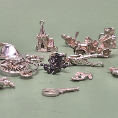 Lot 65 - A collection of unhallmarked silver charms to...