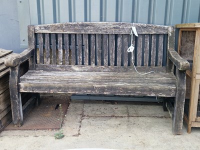 Lot 469 - A rustic wooden garden bench with slat back...